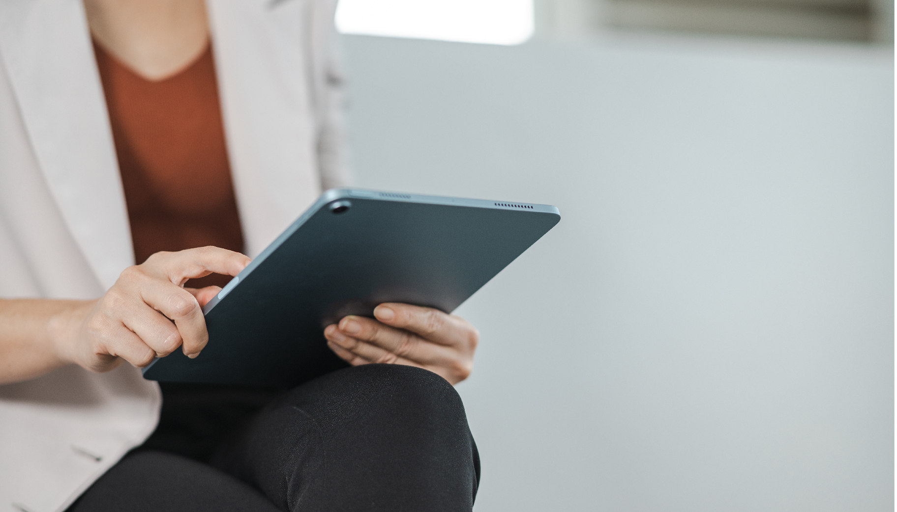 A woman in a white blazer using a tablet computer.